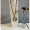 Sans titre Sautoir avec médaillon d'un diamètre de 65 mm, couleurs beige et rose.